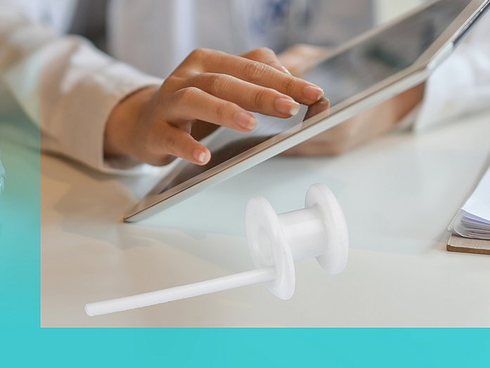 Eine Ärztin bedient ein Tablet, daneben liegt eine Stimmprothese